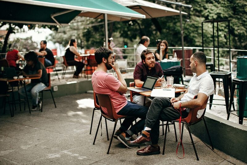 Three people meet at outside table